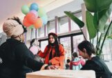 Artist Tianyuan (Margaret) Zheng (in red) engages with participants during Bright Spot: Pie with Wide Tim